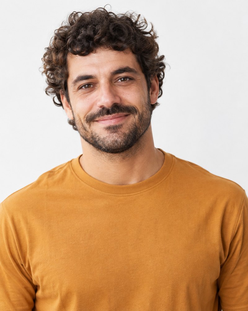 Nuno Caeiro, cabelo encaracolado, camisa âmbar lisa, estúdio claro